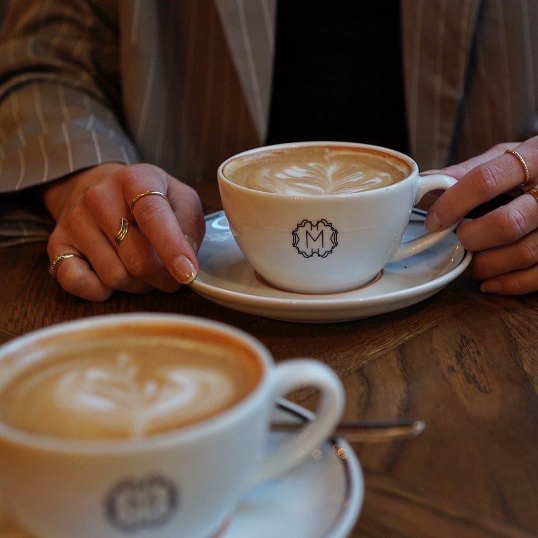Två kaffekoppar med Bistro Maries monogram, serverade vid ett bord i Gamla stan