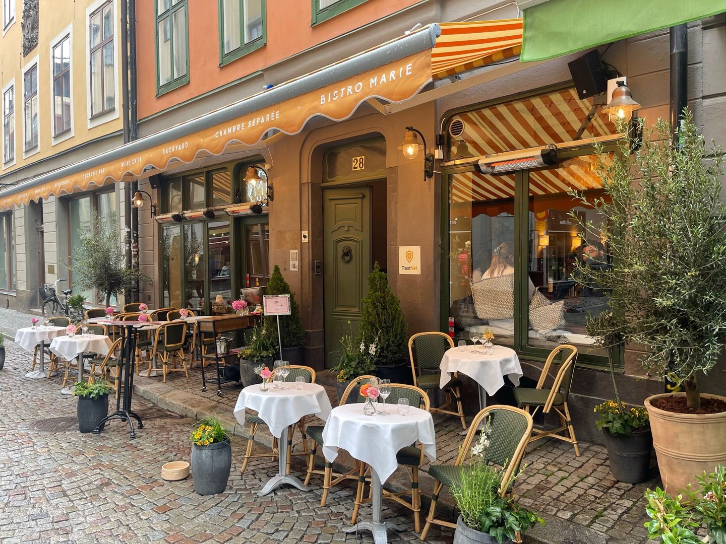Uteserveringen på Bistro Marie en sommarkväll, dukade bord under den randiga markisen på Stora Nygatan i Gamla Stan